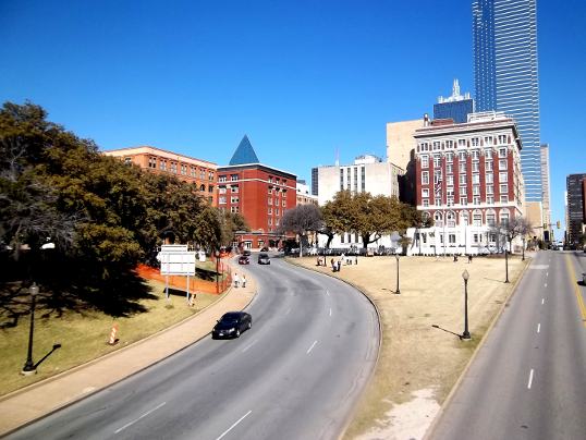 The view a little to the left of Main Street. That's the curve of Elm Street. The grassy knoll is on the left, the Texas Schoolbook Depository is the lighter brick building over the trees. The assassination site is right in front of the two cars coming down the road. 