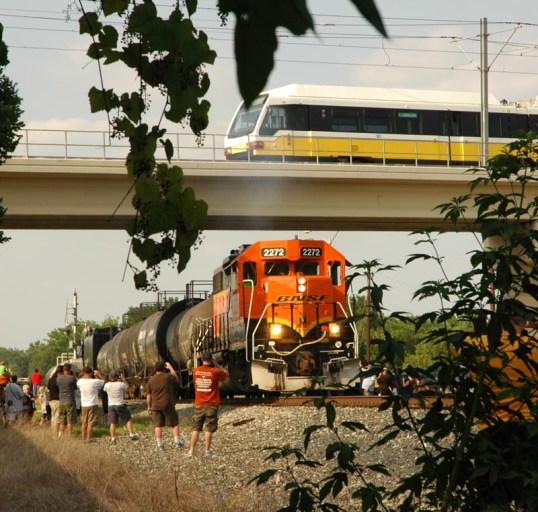 Three generations. The smoking diesel pulling the steam Big Boy, while the electric DART train zooms by overhead.